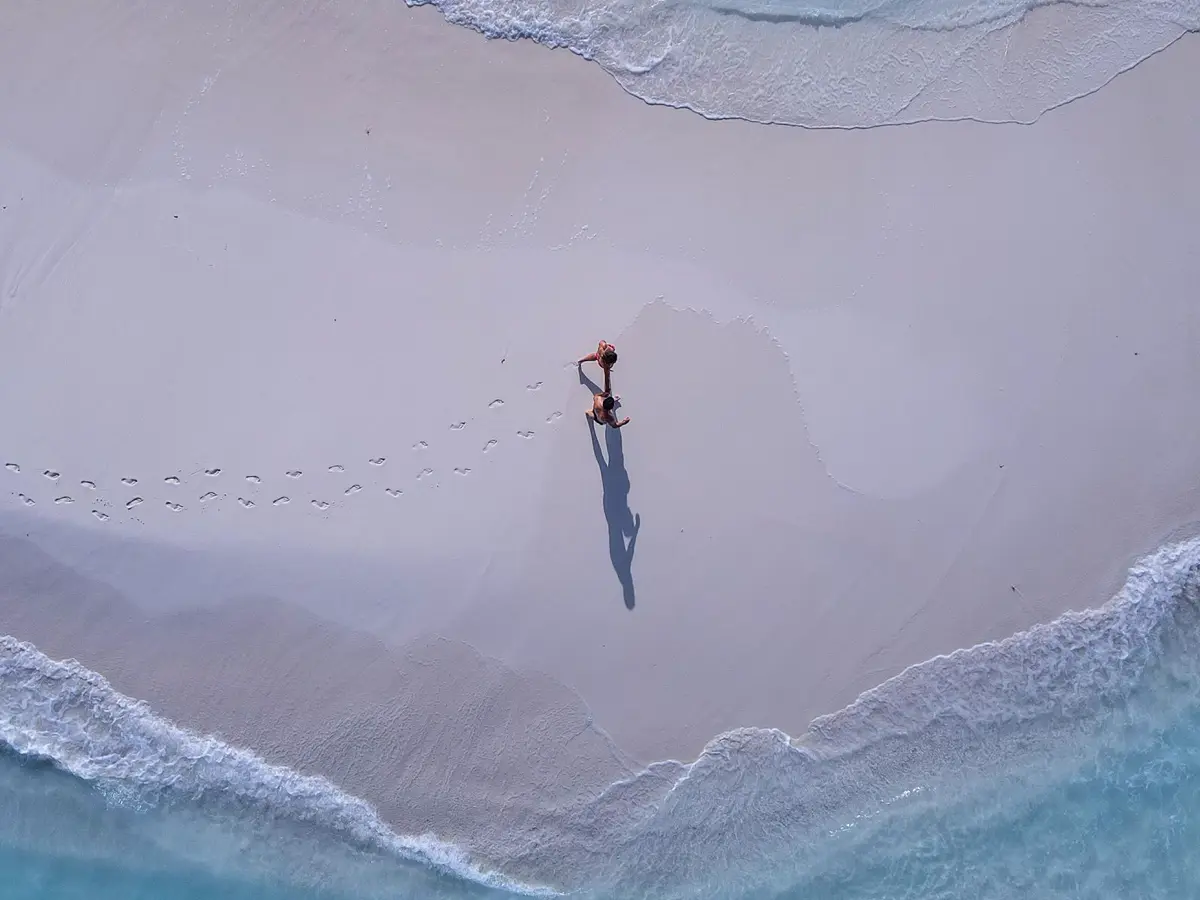 An aerial view of a white sand beach meeting turquoise water.