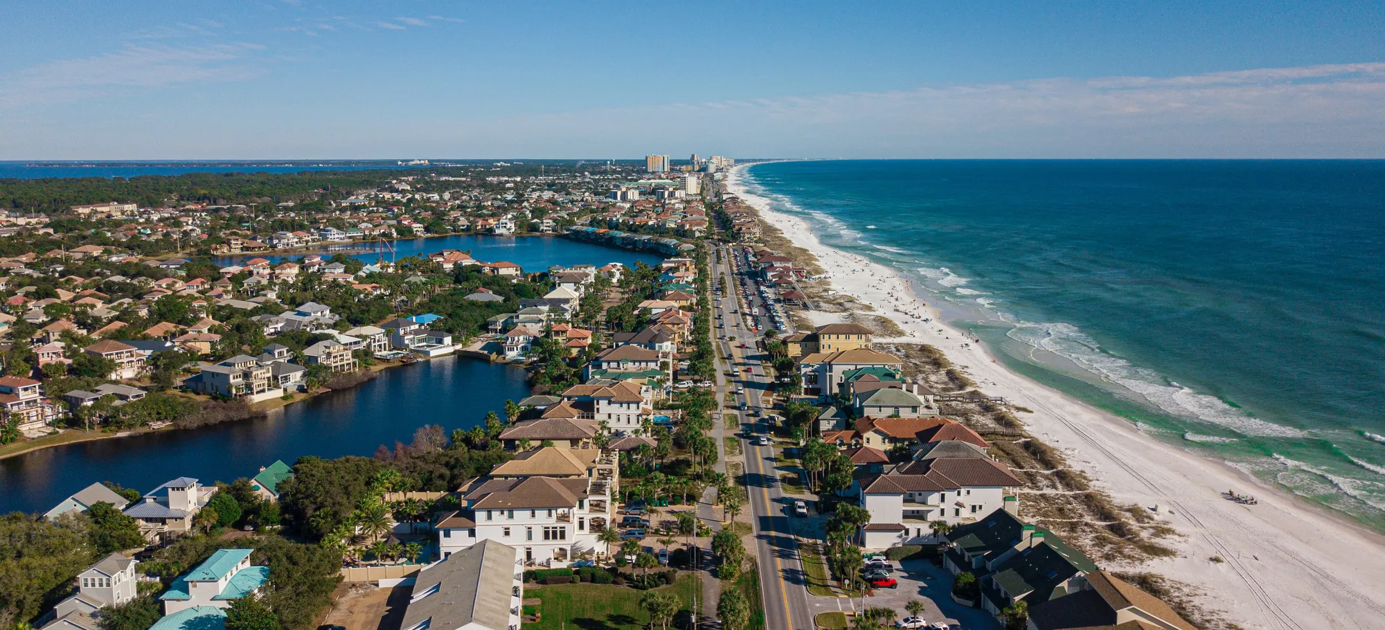 Houses along a stretch of Florida coastline seen from the air, with the beach and open water beyond.